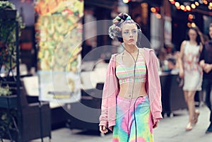 Rebel fashion woman on the streets with trendy eyeglasses and piercings, listening music on headphones - Unique Avant- photo