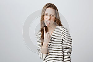 Rebel teenager stand against rules and control. Portrait of cool and confident girl with fair hair sticking out tongue