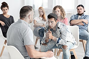 Rebellious spanish man listening to psychologist during group therapy for teenagers