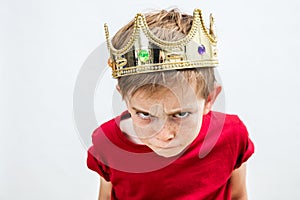 Rebellious spoiled kid with crown for mad attitude, high angle photo