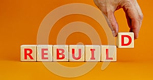 Rebuild and build symbol. The concept word Rebuild on wooden cubes. Beautiful orange table, orange background, copy space.