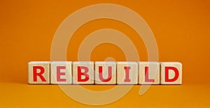 Rebuild and build symbol. The concept word Rebuild on wooden cubes. Beautiful orange table, orange background, copy space.