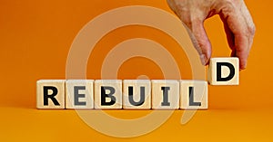 Rebuild and build symbol. The concept word Rebuild on wooden cubes. Beautiful orange table, orange background, copy space.
