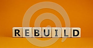 Rebuild and build symbol. The concept word Rebuild on wooden cubes. Beautiful orange table, orange background, copy space.