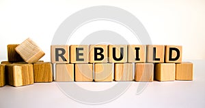 Rebuild and build symbol. The concept word Rebuild on wooden cubes. Beautiful white table, white background, copy space. Business