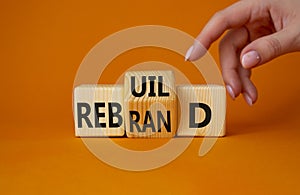 Rebuild and Rebrand symbol. Businessman hand points at turned wooden cubes with words Rebrand and Rebuild. Beautiful orange