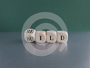 Rebuild symbol. Concept green word rebuild on wooden cubes on a beautiful grey table. Green background. Business and rebuild