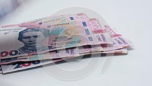 Recalculation of money. Hands count Ukrainian hryvnia bills on white background. Two hundred hryvnia banknotes pack. Banknotes