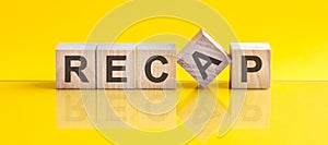 RECAP word is made of wooden building blocks lying on the yellow table, concept photo