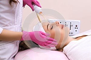 Receiving electric darsonval facial massage procedure.