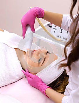 Receiving electric darsonval facial massage procedure.