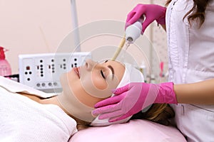 Receiving electric darsonval facial massage procedure.