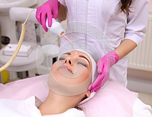 Receiving electric darsonval facial massage procedure.