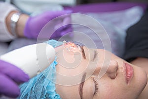 Receiving electric darsonval facial massage procedure at salon