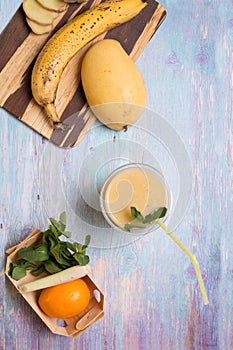 Recepie of healthy fresh yellow fruit mango smoothie at blue table