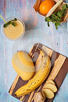 Recepie of healthy fresh yellow fruit mango smoothie at blue table