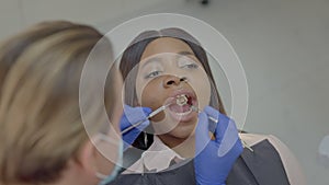 Reception At Dentist. In Chair Sits Black Young Girl. Tablet. Doctor In Medical Gloves And Mask.