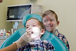 Reception at the dentistry. A little boy lays on the couch and his brother stays behind