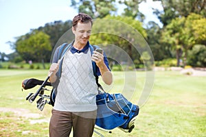 The reception here is pretty good. Smiling golfer using his mobile on the course while carrying his clubs.