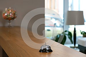 Reception at the hotel with a bell on a wooden table, closeup view.