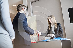 Receptionist giving identity card to businessman at convention center