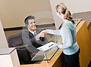 Receptionist greeting woman at front desk