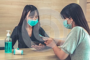 Receptionist and guest wearing face mask at front desk .