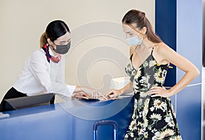 Receptionist hands over a passport to a tourist at te front desk and reception of a hostel