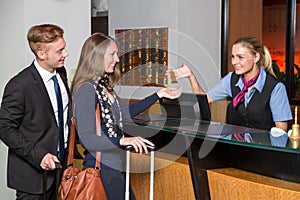 receptionist at hotel reception handing over key to guest or customer