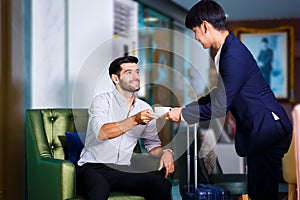 Receptionist man giving hot coffee to young guests man