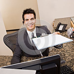 Receptionist offering clipboard and pen