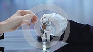 Receptionist passing booked key chain to client, hotel business, hospitality