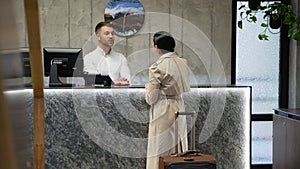 Receptionist talking with guest businesswoman at hotel front desk