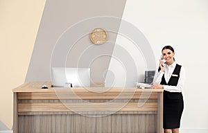 Receptionist talking on telephone near desk in hotel