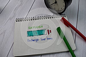 Recharge Your Iman - Ramadan Kareem Quotes write on a book isolated on wooden background. Ramadan concept