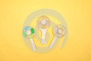 Rechargeable mini portable electric fan on a yellow background