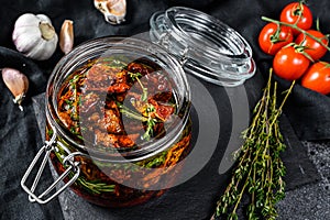 Recipe for cooking dried tomatoes in olive oil with spices and herbs. Black background. Top view