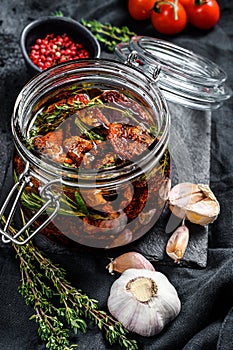 Recipe for cooking dried tomatoes in olive oil with spices and herbs. Black background. Top view