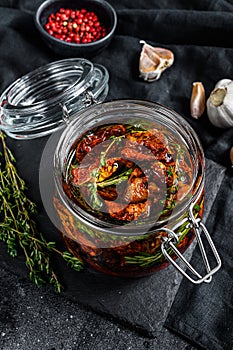Recipe for cooking dried tomatoes in olive oil with spices and herbs. Black background. Top view