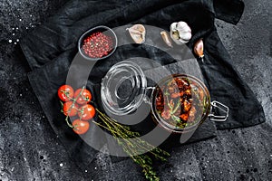 Recipe for cooking dried tomatoes in olive oil with spices and herbs. Black background. Top view