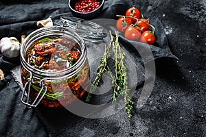 Recipe for cooking dried tomatoes in olive oil with spices and herbs. Black background. Top view. Copy space