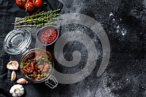 Recipe for cooking dried tomatoes in olive oil with spices and herbs. Black background. Top view. Copy space