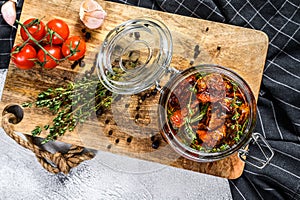 Recipe for cooking dried tomatoes in olive oil with spices and herbs. Gray background. Top view