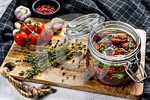 Recipe for cooking dried tomatoes in olive oil with spices and herbs. Gray background. Top view