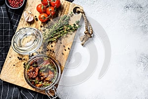 Recipe for cooking dried tomatoes in olive oil with spices and herbs. Gray background. Top view. Copy space