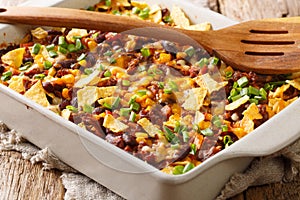 Recipe for a delicious frito pie with ground beef, cheese, corn, beans and chips close-up in a baking dish. horizontal