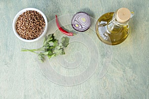 recipe or food composition or nutrition concept. buckwheat with spices and olive oil on green wooden background