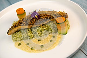 Recipe for fried fillet of sea bass with herb risotto, white wine sauce, fresch creme, roll of carrot and courgette