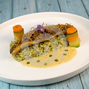 Recipe for fried fillet of sea bass with herb risotto, white wine sauce, fresch creme, roll of carrot and courgette