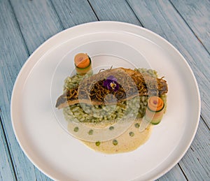 Recipe for fried fillet of sea bass with herb risotto, white wine sauce, fresch creme, roll of carrot and courgette